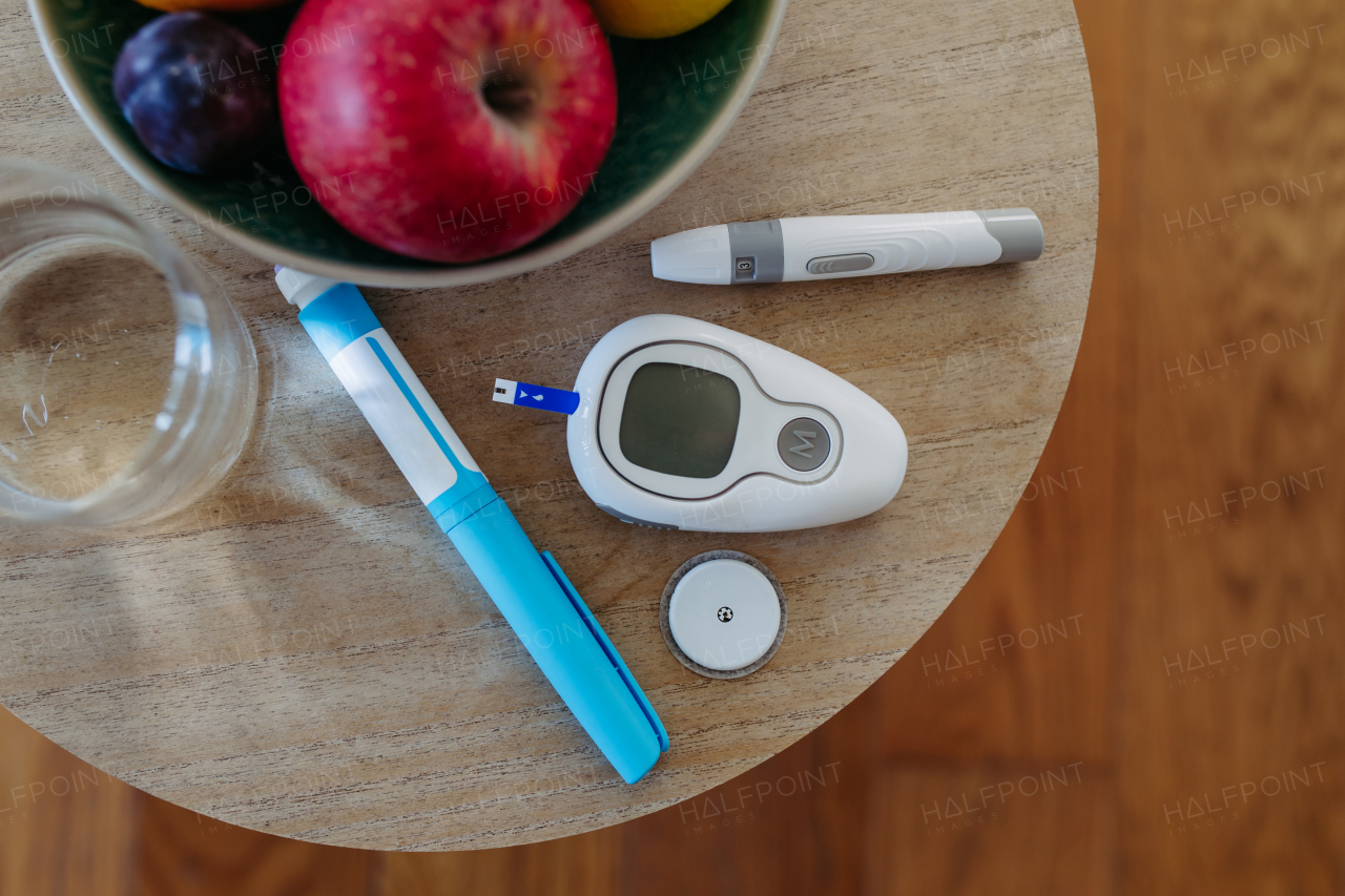 Close up of diabetes supplies and devices on table. Continuous glucose monitor, insulin pen, blood glucose meter. Banner with copy space.