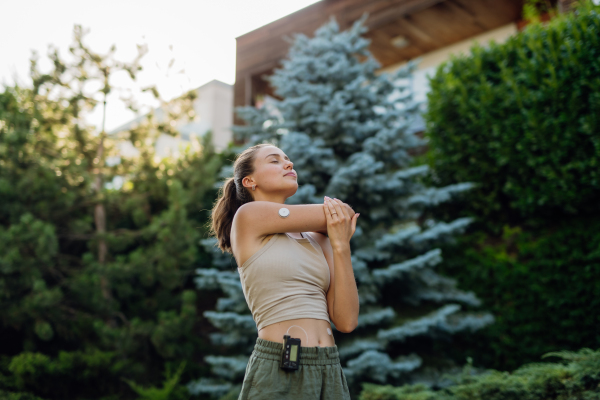 Beautiful diabetic woman preparing for outdoor run in the city. Young woman wearing an insulin pump during exercising. Concept of exercise and diabetes.