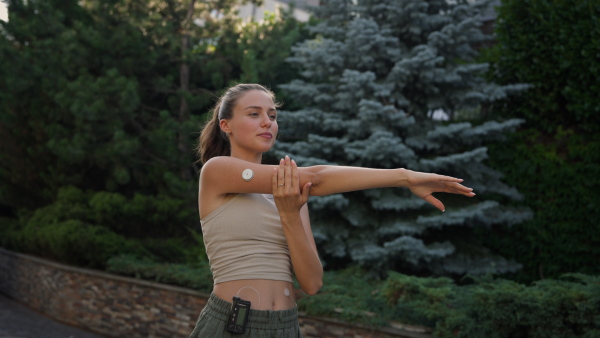 Beautiful diabetic woman preparing for outdoor workout in the city. Young woman wearing an insulin pump during exercising. Concept of exercise and diabetes. Banner with copy space.