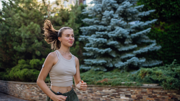 Beautiful diabetic woman running outdoor, in the city. Young woman wearing an insulin pump during exercising. Concept of exercise and diabetes.