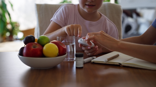 Nurse checking girl's blood glucose level using a fingerstick glucose meter. Endocrinologist waiting for results from his blood test.