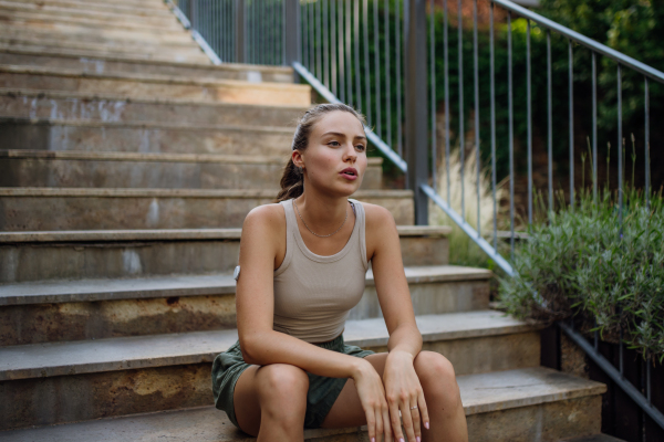 Beautiful diabetic woman feeling dizzy after running workout in the city. Young woman wearing an insulin pump during exercising. Concept of exercise and diabetes.