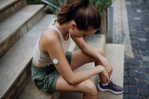 Beautiful diabetic woman feeling dizzy after running workout in the city. Young woman wearing an insulin pump during exercising. Concept of exercise and diabetes.