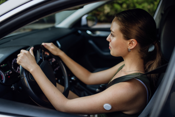 Woman with diabetes monitoring her blood sugar during car drive. Diabetic woman with CGM needs to raise her blood sugar level to continue driving.