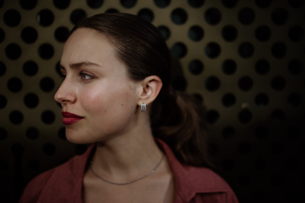 Profile portrait of a stunning woman with green eyes. Headshot of a woman standing in the darkness.