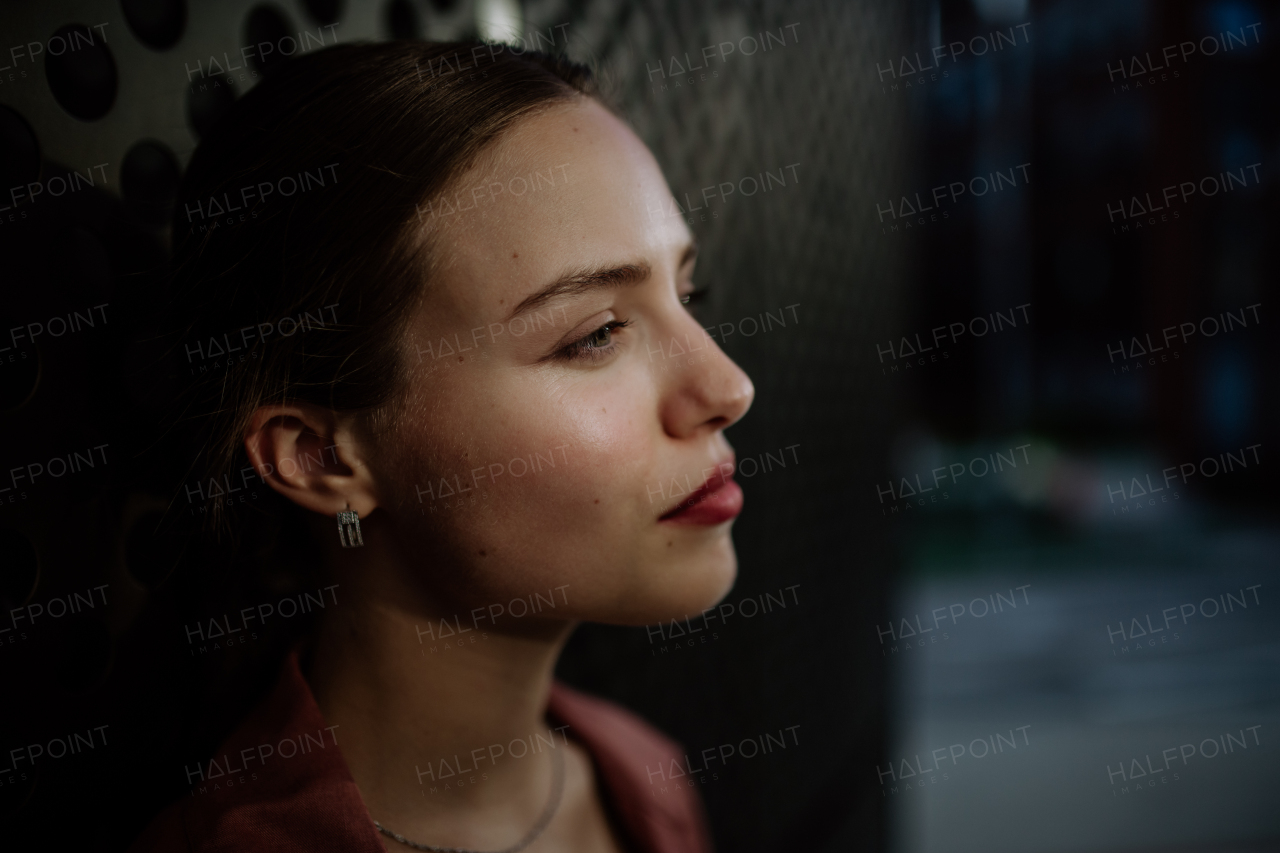 Profile portrait of a stunning woman with green eyes. Headshot of a woman standing in the darkness.