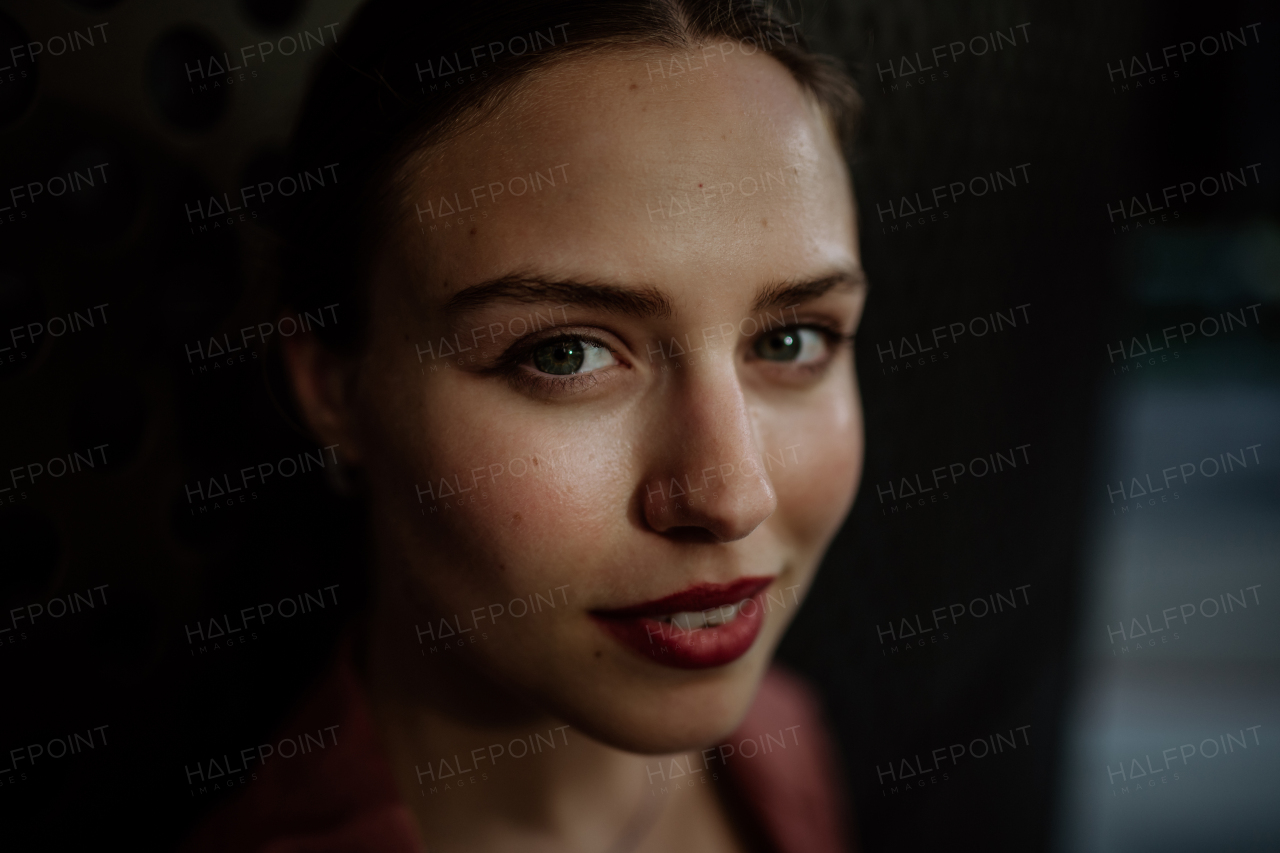 Portrait of a stunning woman with green eyes. Headshot of a woman standing in the darkness.