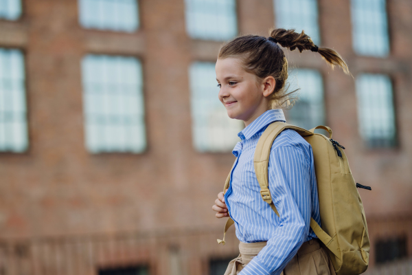 Side view of a girl with a backpack going to school in the morning. Schoolgirl returns home after a long day at school. Concept of back to school.