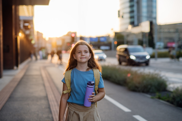 Front view of a girl with a backpack goging to school in the morning. Schoolgirl returns home after a long day at school. Concept of back to school.