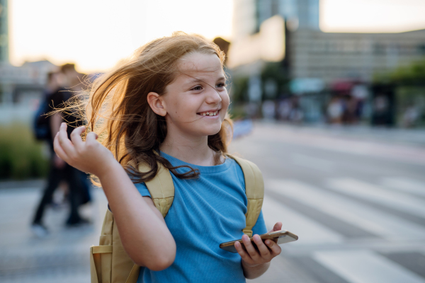 Front view of a smiling girl with a backpack going to school in the morning. Schoolgirl returns home after a long day at school. Concept of back to school.