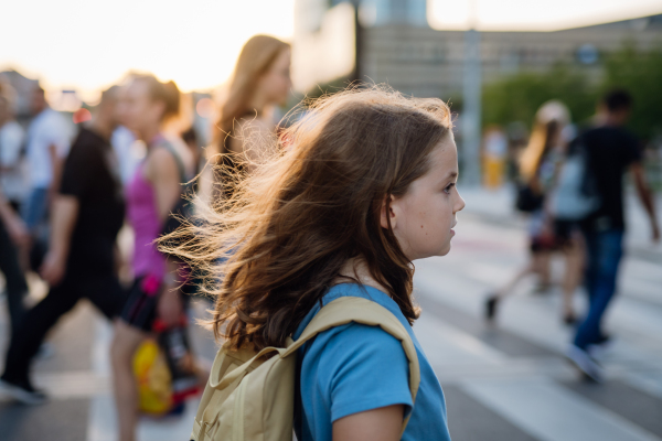 Side view of a girl with a backpack crossing the pedestrian crosswalk on her way to school. Concept of back to school.