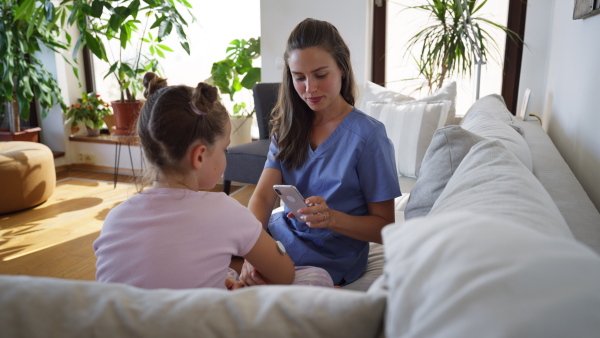 Nurse applying a continuous glucose monitor sensor to the arm of a diabetic girl. CGM device making life of school girl easier, helping manage his illness and focus on other activities.