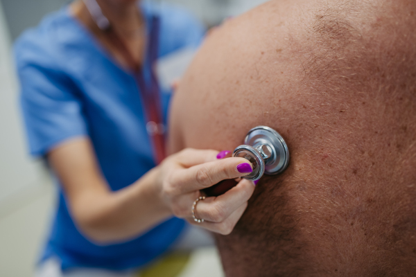 Female doctor listening to the bowel sounds of overweight patient using stethoscope. Obesity affecting middle-aged men's health. Concept of health risks of overwight and obesity.