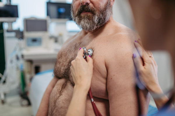 Female doctor listening to heartbeats and rhytm of overweight patient using stethoscope, detecting murmurs, irregularities, heart palpitations. Obesity affecting middle-aged men's health. Concept of health risks of overwight and obesity.