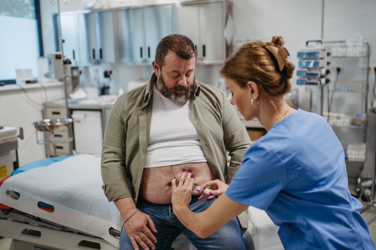 Doctor is injecting insulin into a patient's abdomen using insulin pen. Obese, overweight man is at risk of developing type 2 diabetes. Concept of health risks of overwight and obesity.