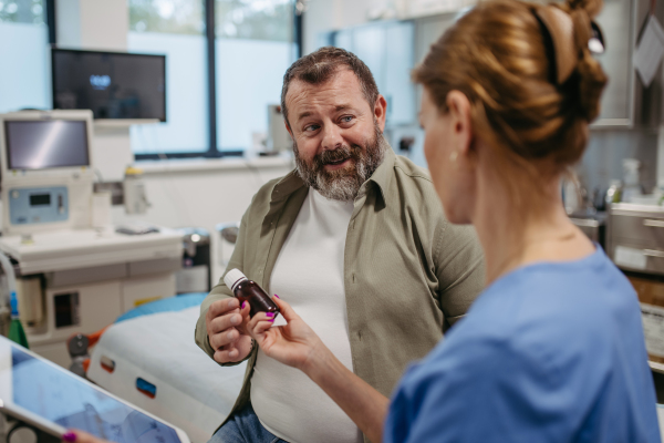 Doctor is prescribing medication to a patient, handing him a bottle of pills. Obesity affecting middle-aged men's health. Concept of health risks of overwight and obesity.