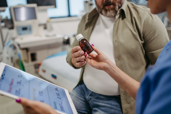 Doctor is prescribing medication to a patient, handing him a bottle of pills. Obesity affecting middle-aged men's health. Concept of health risks of overwight and obesity.