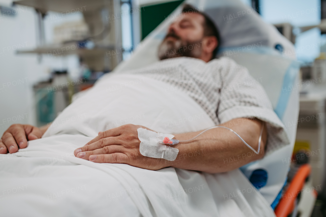 Patient with IV cannula in vein, hand lying in hospital bed. Man in intensive care unit in hospital. IV, intravenous therapy for the overweight man.