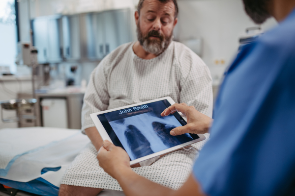 Doctor showing overweight patient chest x-ray, discussing test result in the emergency room. Respiratory diseases in middle-aged men's health. Concept of health risks of overwight and obesity.