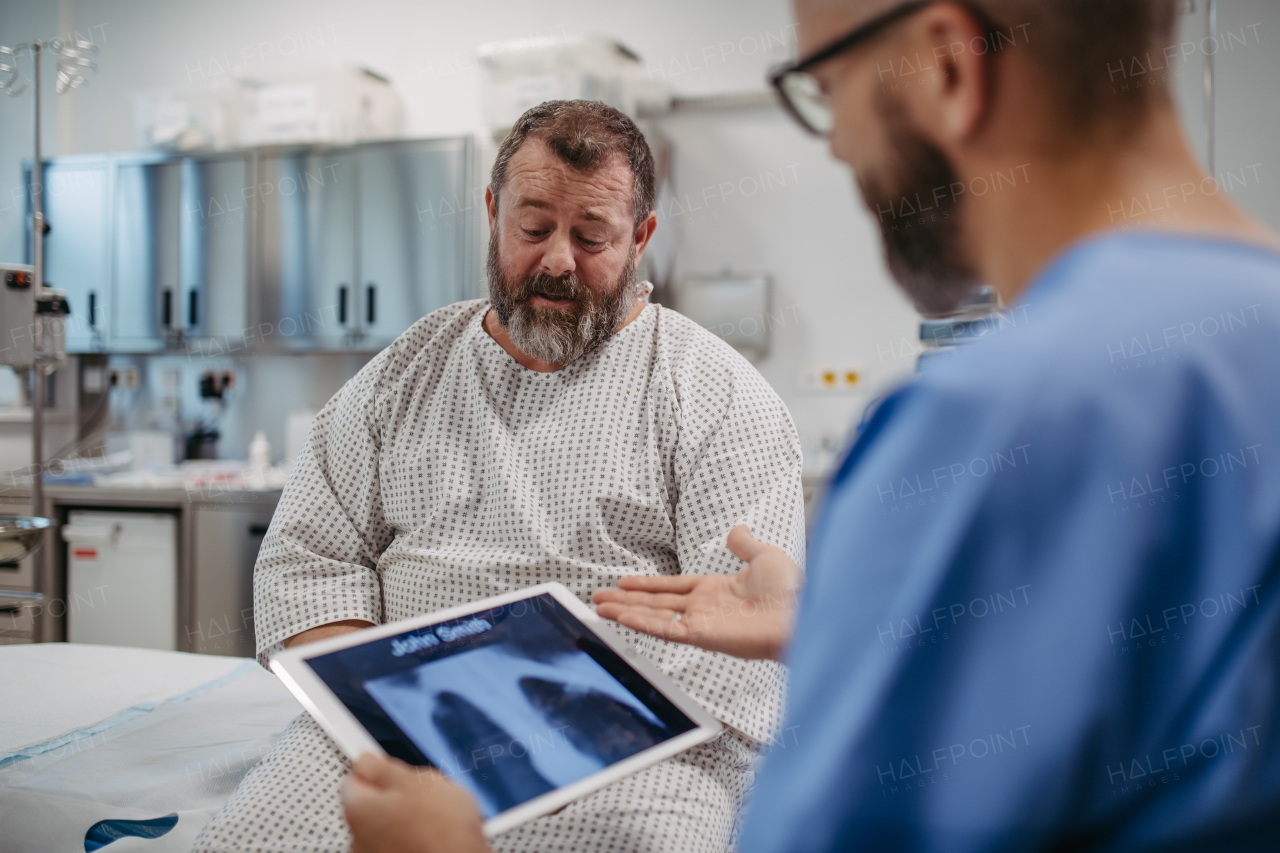 Doctor showing overweight patient chest x-ray, discussing test result in the emergency room. Respiratory diseases in middle-aged men's health. Concept of health risks of overwight and obesity.