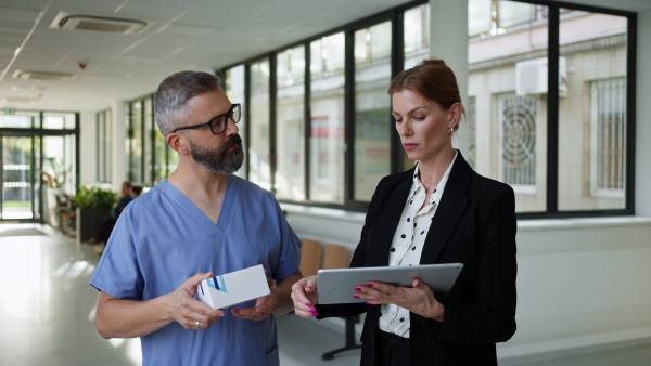 Pharmaceutical sales representative talking with doctor in medical building. Ambitious female hospital director consulting with healtcare staff. Woman business leader.