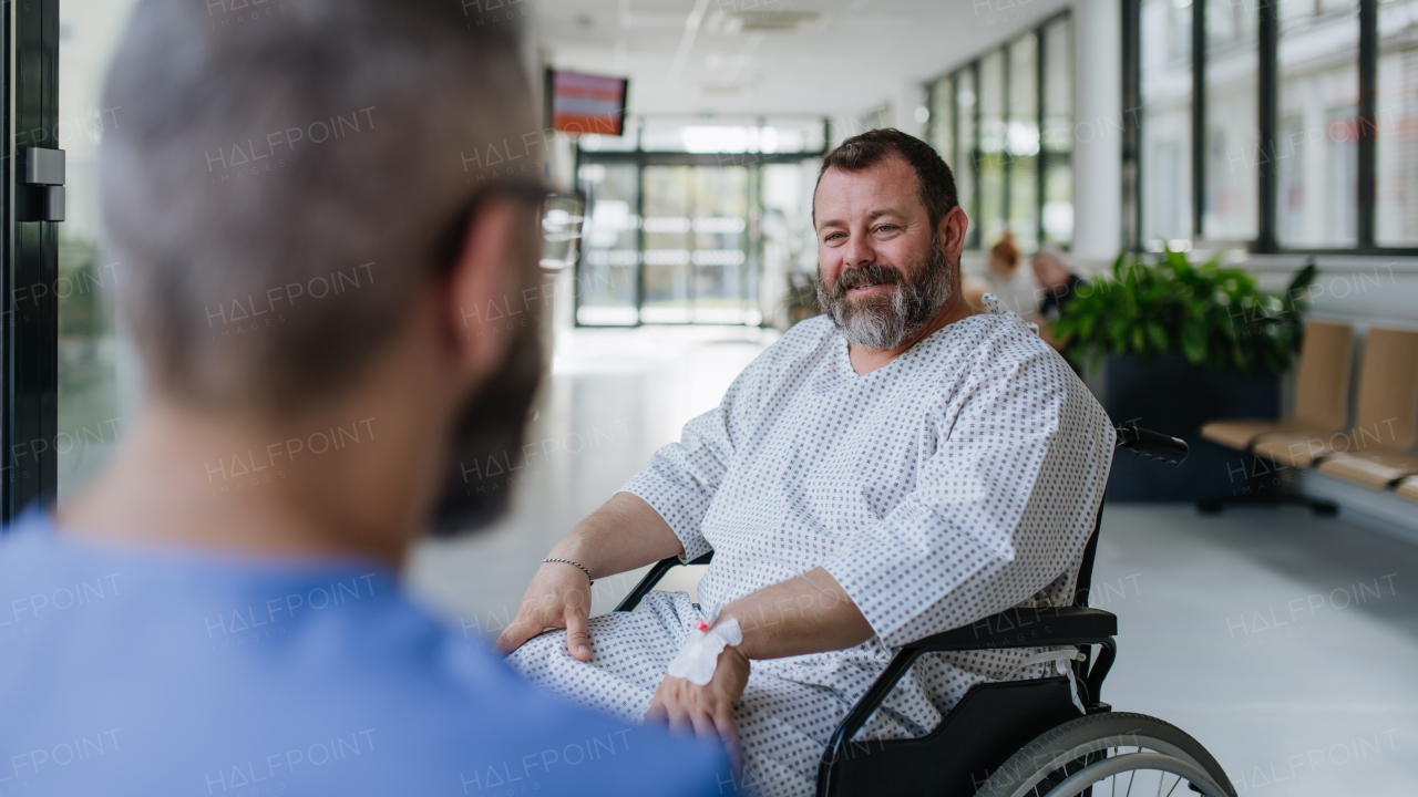 Close up of supportive doctor talking with worried overweight patient in wheelchair. Illnesses and diseases in middle-aged men's health. Compassionate physician supporting stressed patient. Concept of health risks of obesity.