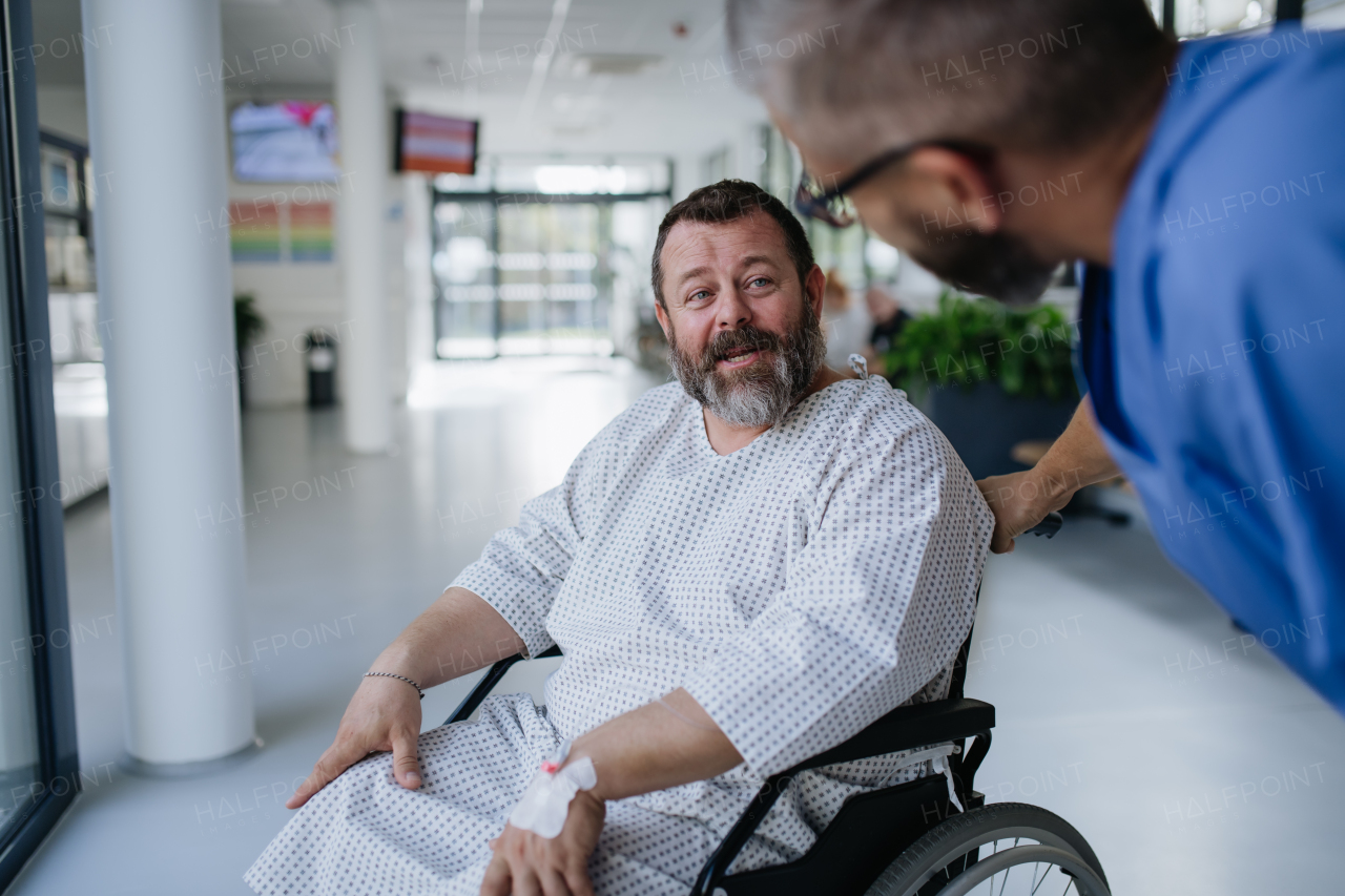 Supportive nurse soothing worried patient in wheelchair. Illnesses and diseases in middle-aged men's health. Compassionate physician talking with stressed patient. Concept of health risks of overwight and obesity.