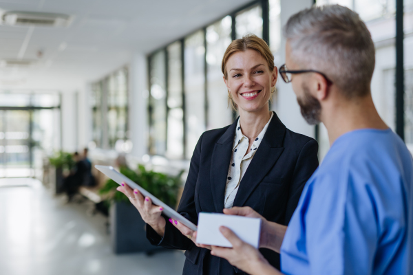 Pharmaceutical sales representative talking with doctor in medical building. Ambitious female hospital director consulting with the healtcare staff. Woman business leader.