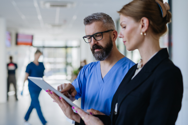 Pharmaceutical sales representative talking with doctor in medical building. Ambitious female hospital director consulting with healtcare staff. Woman business leader.