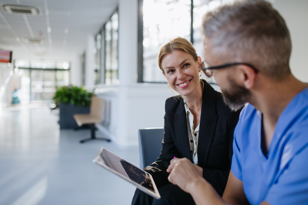 Pharmaceutical sales representative talking with doctor in medical building. Ambitious female sales representative presenting new medication, pills. Woman business leader.