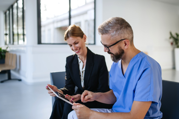 Pharmaceutical sales representative talking with doctor in medical building. Ambitious female sales representative presenting new medication, pills. Woman business leader.