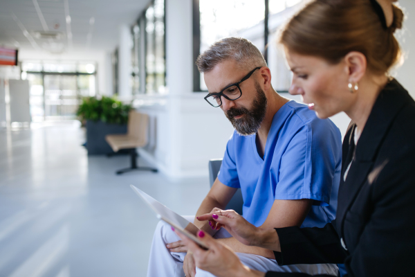 Pharmaceutical sales representative talking with doctor in medical building. Ambitious female sales representative presenting new medication, pills. Woman business leader.