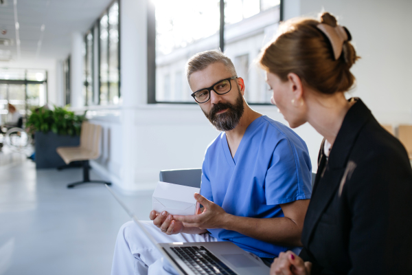 Pharmaceutical sales representative talking with doctor in medical building. Ambitious female sales representative presenting new medication, pills. Woman business leader.