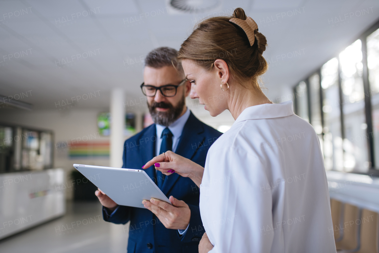 Pharmaceutical sales representative talking with the female doctor in medical building. Hospital director consulting with healthcare staff.