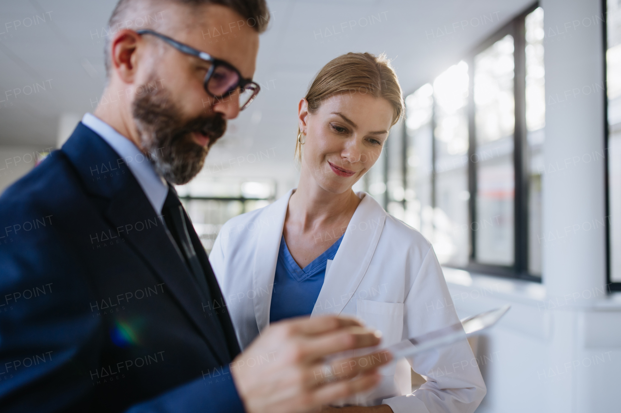 Pharmaceutical sales representative talking with the female doctor in medical building. Hospital director consulting with healthcare staff.