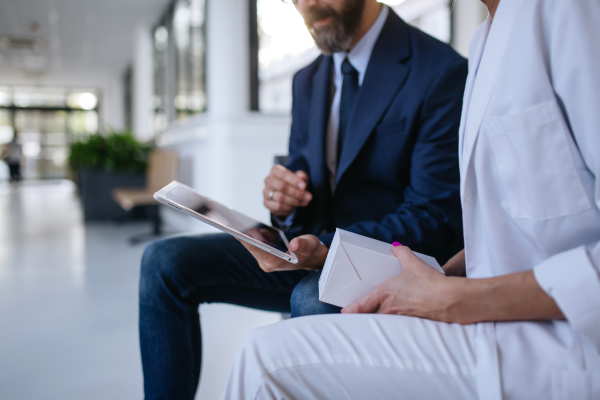 Close up of pharmaceutical sales representative talking with the female doctor in medical building. Hospital director consulting with healthcare staff.