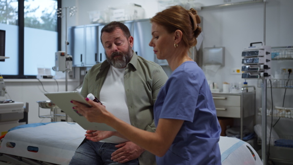 Female doctor consulting with the overweight patient, discussing test result in doctor office. Obesity affecting middle-aged men's health. Concept of health risks of overwight and obesity.