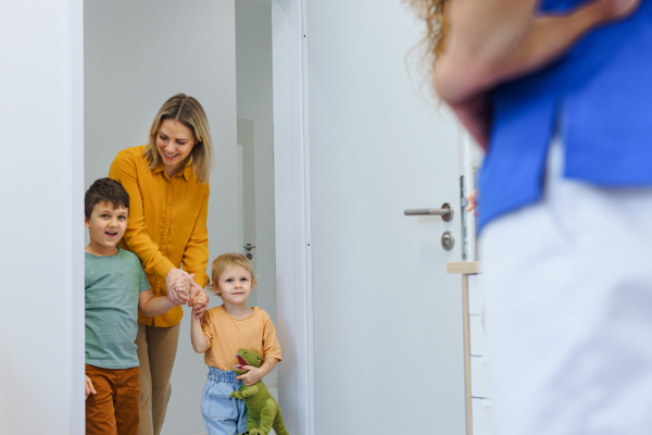 Mother and her little children greeting with multiracial dentist in his office.