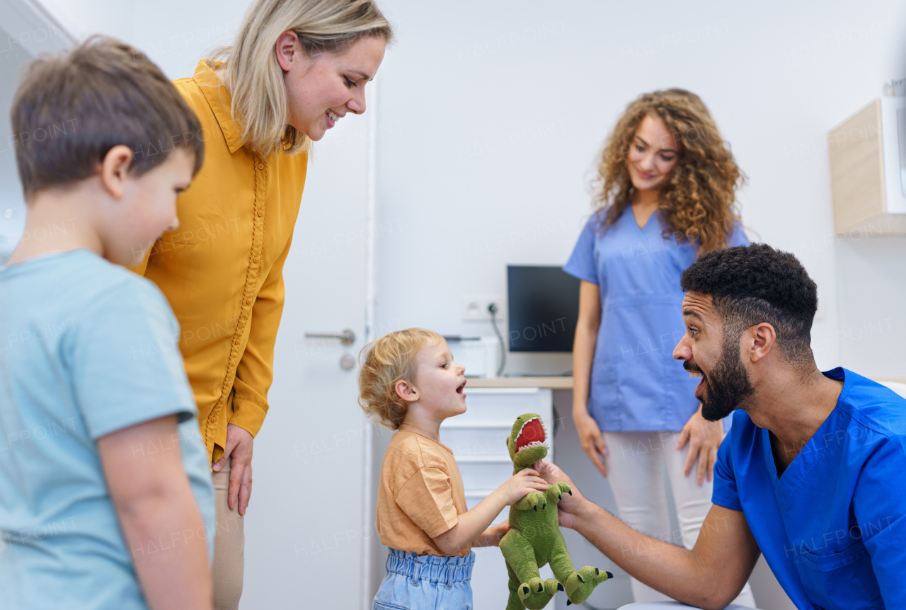 Young multiracial dentist playing with kids at his office in dentist clinic.