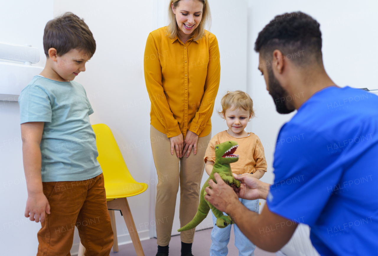 Young multiracial dentist playing with kids at his office in dentist clinic.