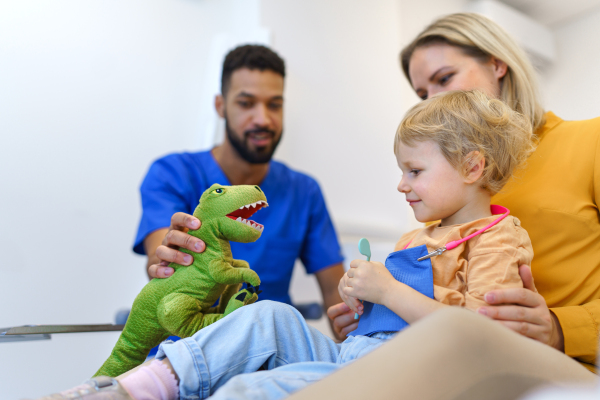 Young multiracial dentist playing with kids at his office in dentist clinic.