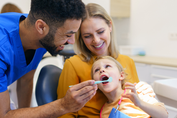 A little girl sitting with her mother on dentists chair during dentist examination.