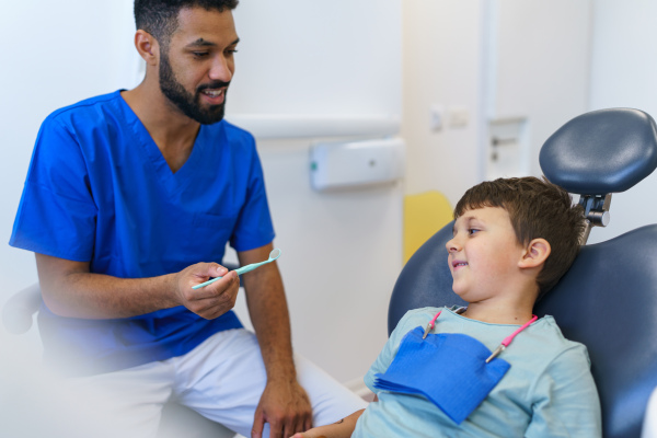 A liitle boy sitting on dentists chair during dentist examination.