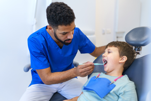 A liitle boy sitting on dentists chair during dentist examination.