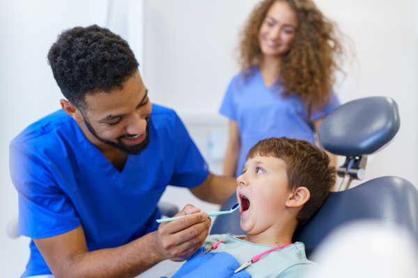 A liitle boy sitting on dentists chair during dentist examination.