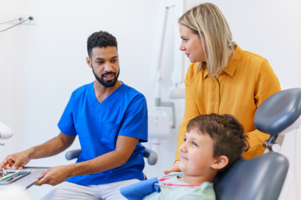 A liitle boy sitting on dentists chair during dentist examination.