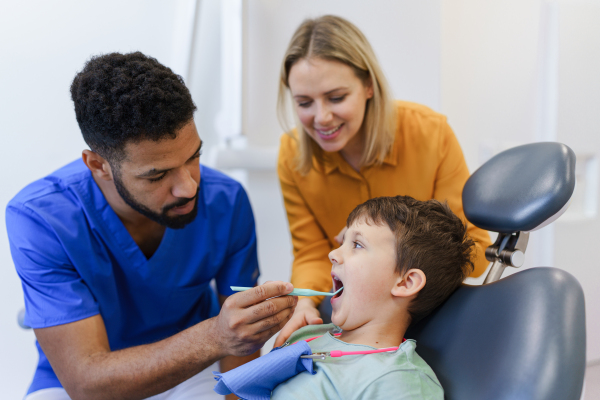 A liitle boy sitting on dentists chair during dentist examination.