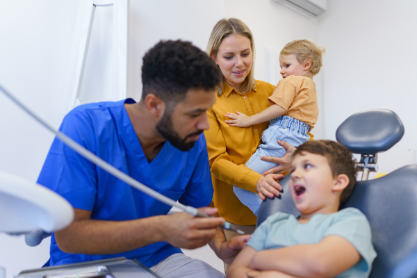 Little unhappy boy sitting in dentists chair, during the examination.