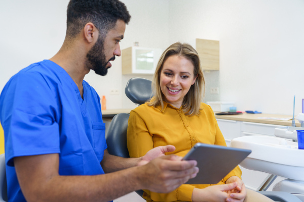 Young woman having consultation with multiracial dentist in his office.