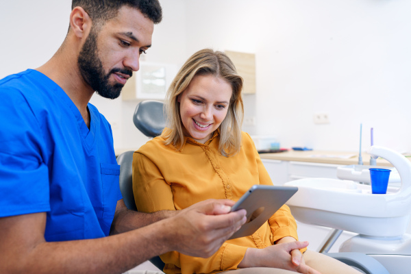 Young woman having consultation with multiracial dentist in his office.